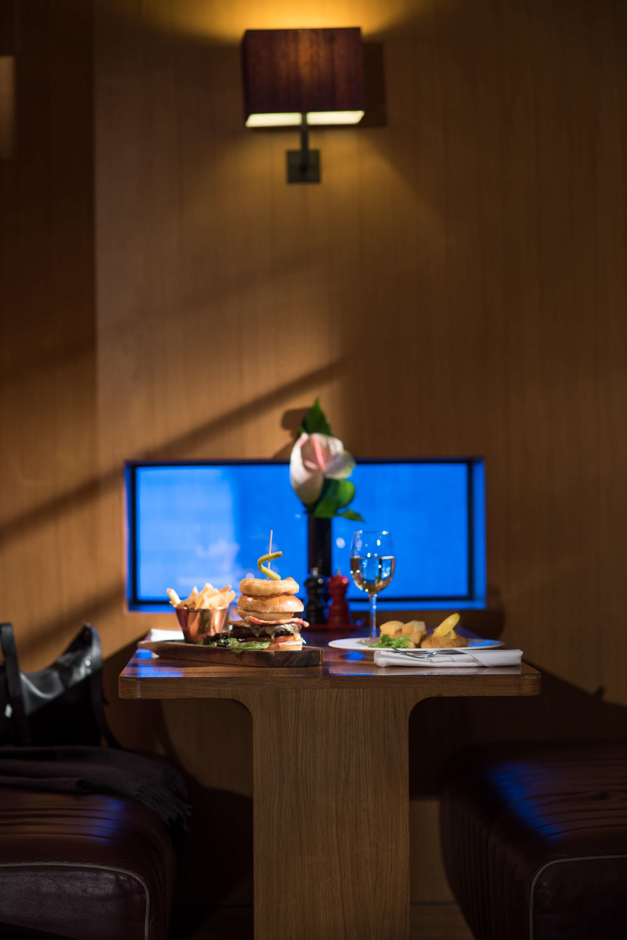 Une table à manger avec un repas, un vase de fleurs et un téléviseur en arrière-plan.