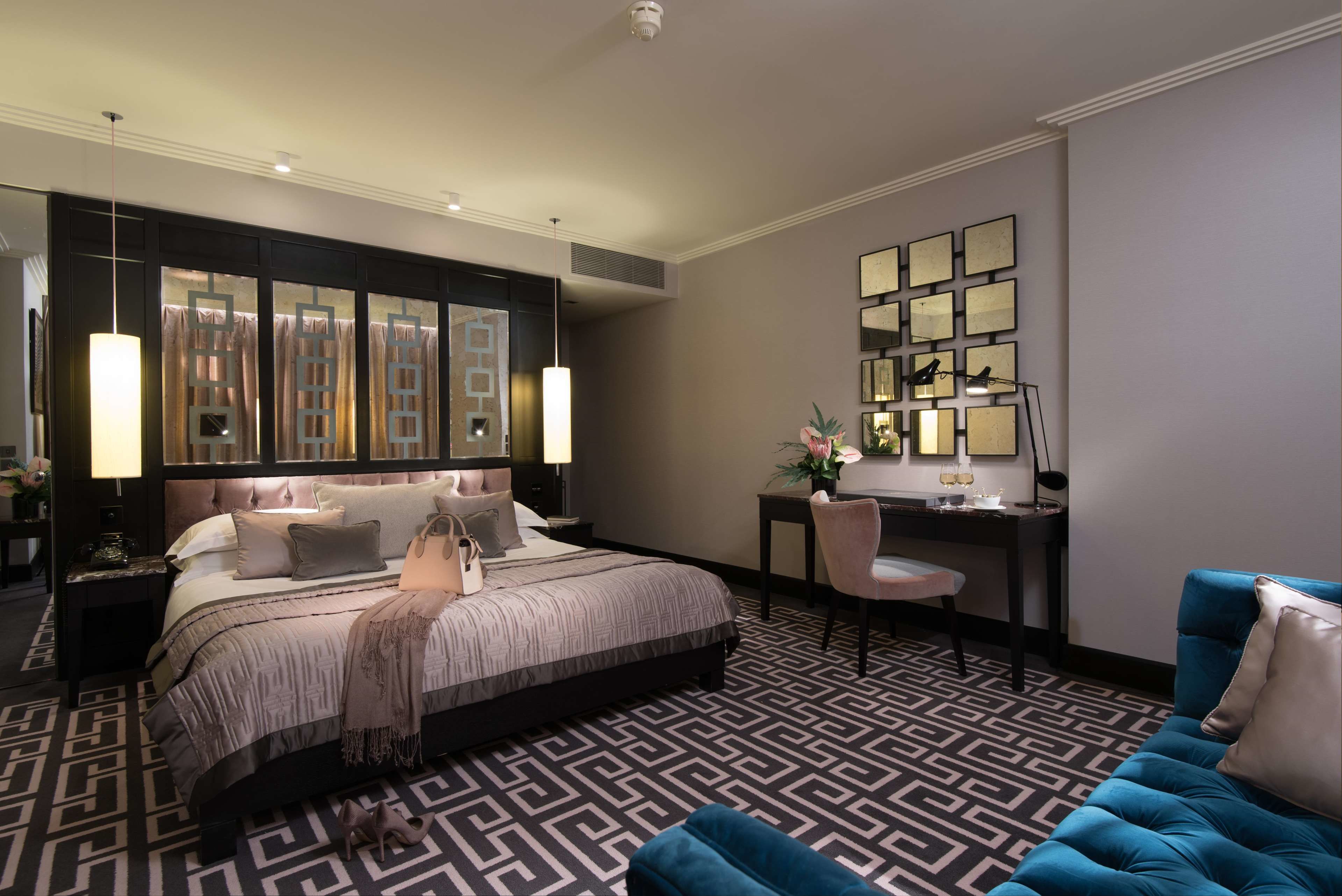 Ein modernes Hotelzimmer mit einem großen Bett, einem Schreibtisch und einem blauen Sofa.