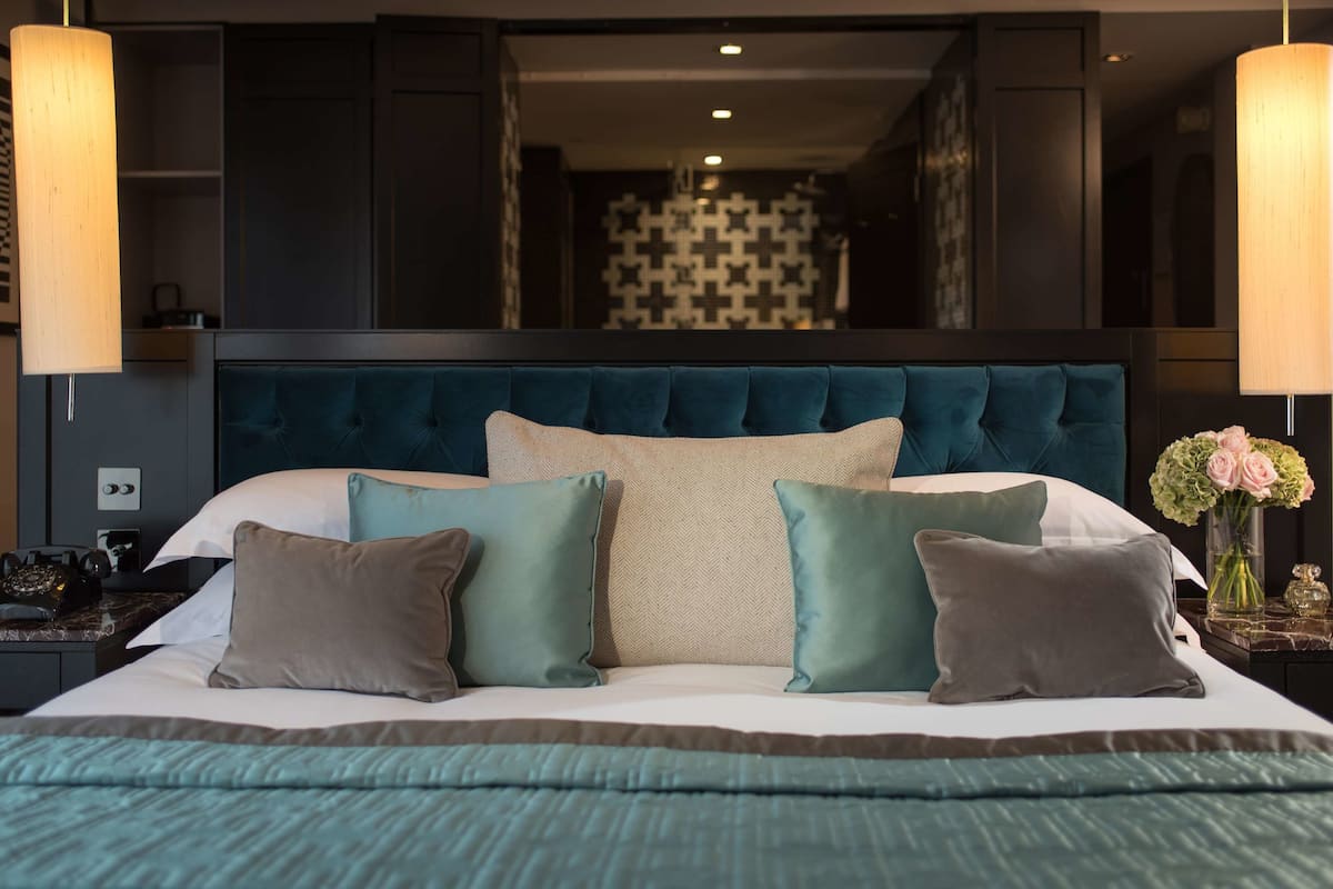 A bedroom with a large bed, a dark headboard, and two bedside tables with lamps.