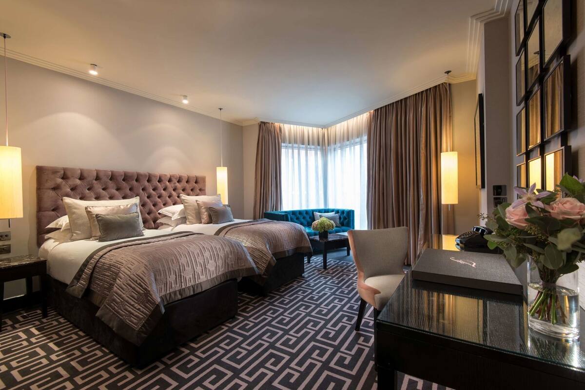 A hotel room with a large bed, a desk, a chair, and a view of the outdoors.