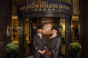 The entrance of The Fitzwilliam Hotel with a circular facade and a sign above the door.