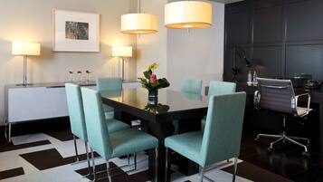 A modern conference room with a black table, teal chairs, and pendant lights.