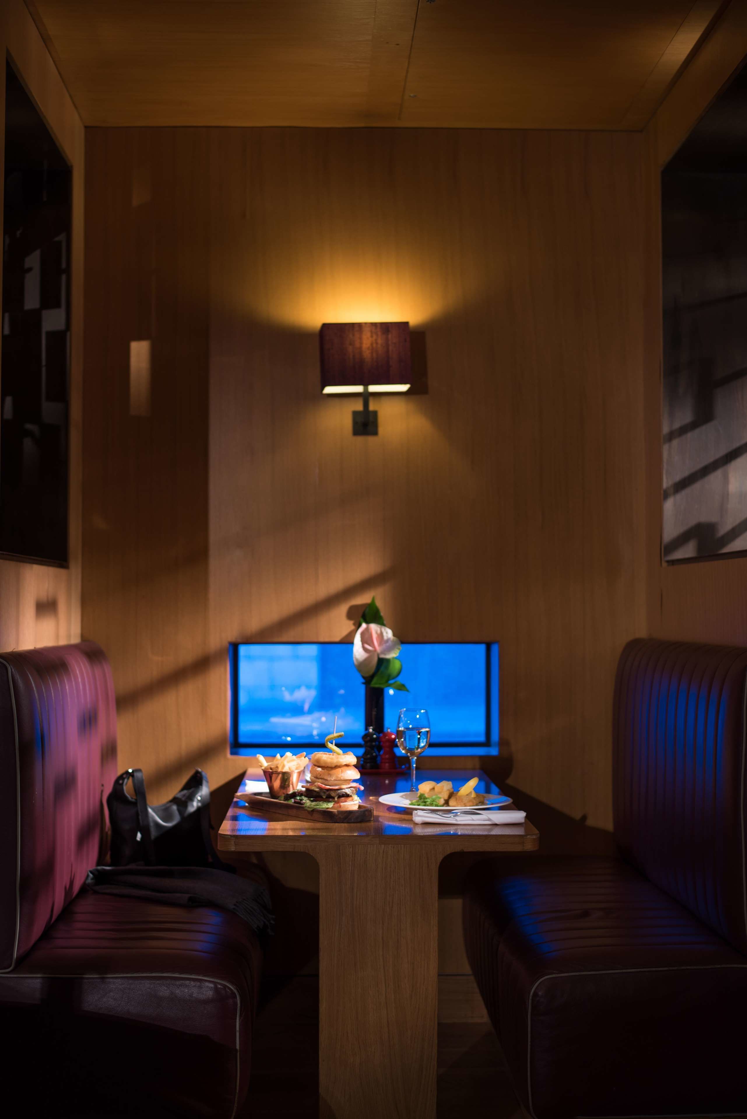 A cozy room with a wooden wall, a television, a table with food, and two leather sofas.