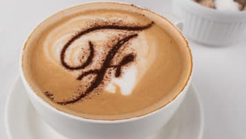 Een kop koffie met latte-art op een witte schotel.
