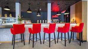 A bar area with red chairs and black pendant lighting. - JUFA Hotel Salzburg (Salzburg)