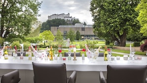 An outdoor dining area with a table set for a meal, chairs, and a view of a castle in the background. - JUFA Hotel Salzburg (Salzburg)