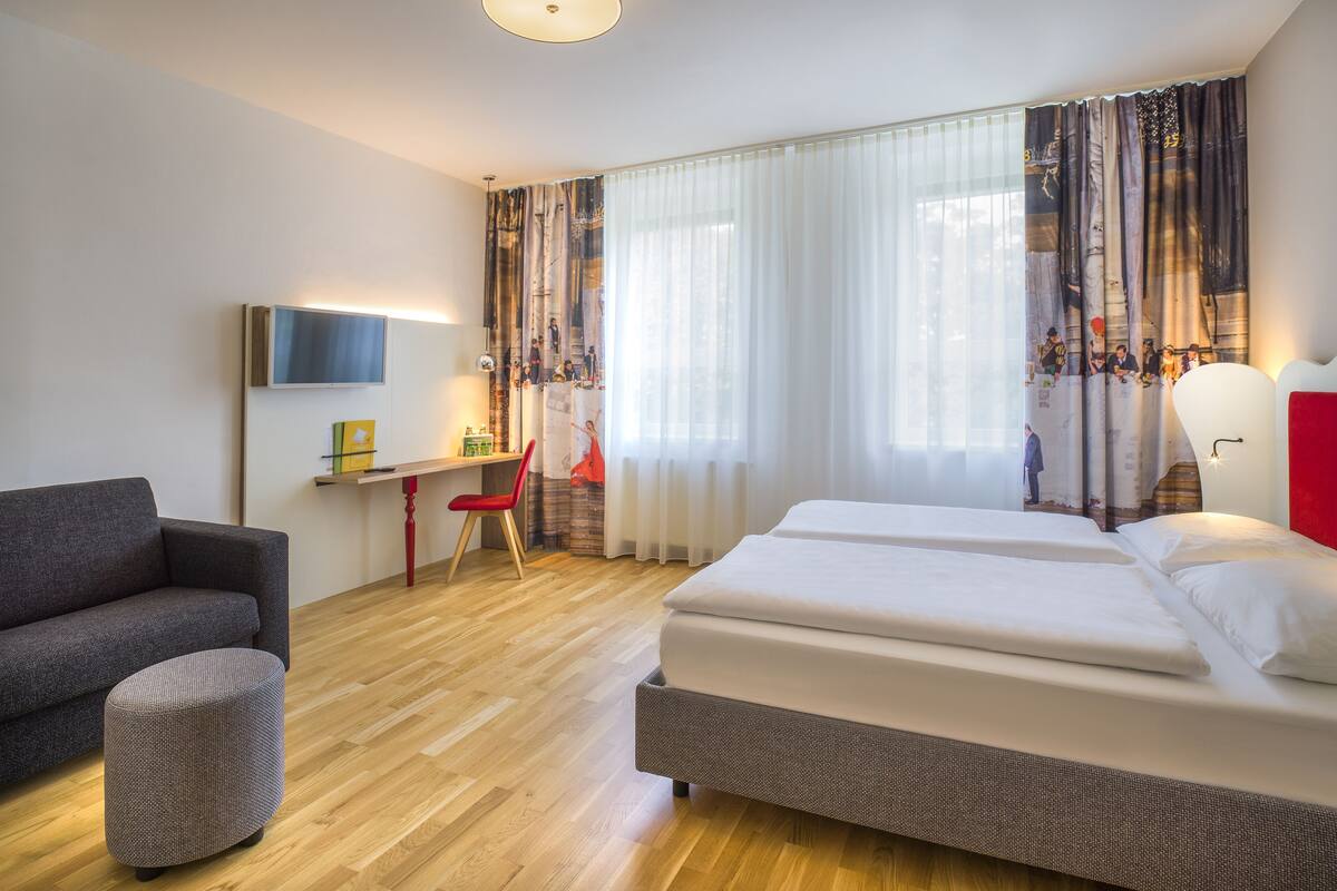 Une chambre d’hôtel avec un lit, un bureau, une chaise et un téléviseur.