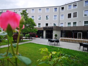 A hotel courtyard with outdoor seating, a signboard, and a building with multiple windows. - JUFA Hotel Salzburg (Salzburg)