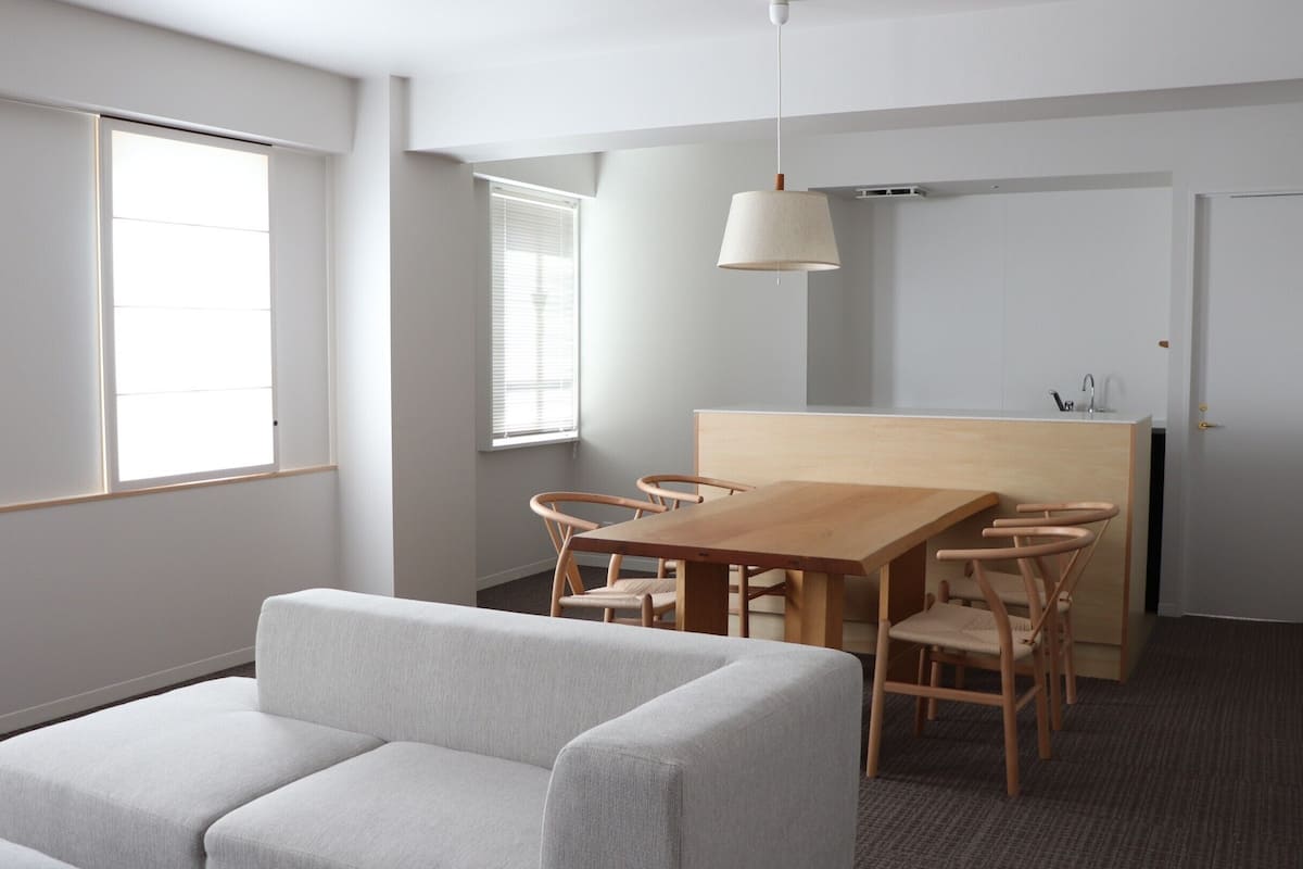 Une pièce moderne et minimaliste, dotée d’une table à manger en bois, de deux canapés confortables et d’un coin cuisine.