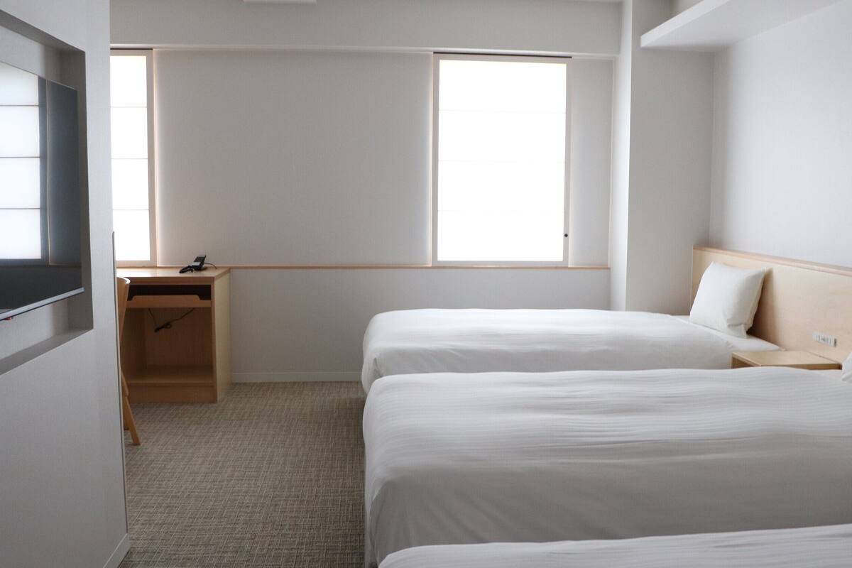 Une chambre d’hôtel avec deux lits, un bureau et une télévision.