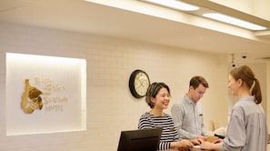 A reception area with a clock, a wall-mounted sign, and a reception desk. - Shin-Osaka Station Hotel (Osaka)