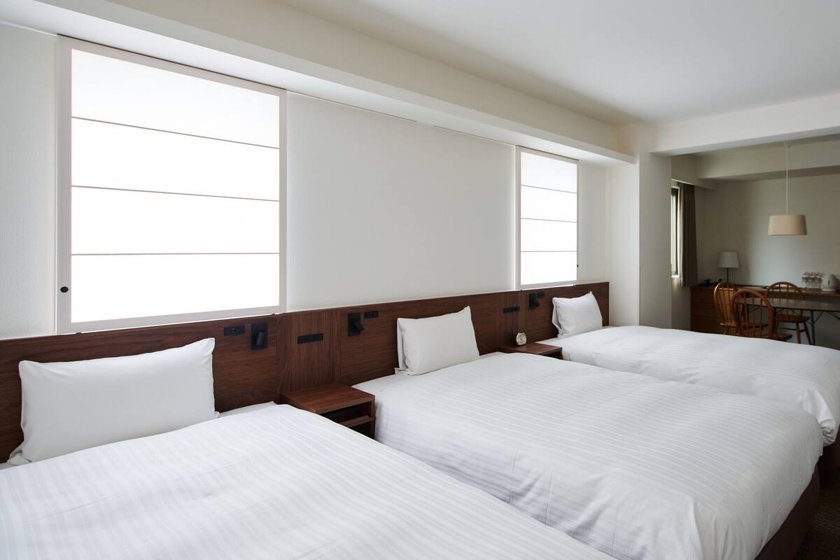 Une chambre d’hôtel avec deux lits, un bureau, un four à micro-ondes et un réfrigérateur.