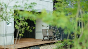 Un espace extérieur moderne, aménagé avec une terrasse en bois, deux chaises et un mur en pierre.