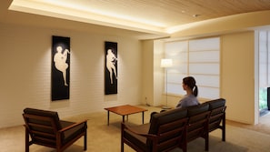 Een kamer met een houten plafond, een groot raam met uitzicht, en twee zwarte kunstwerken aan de muur.