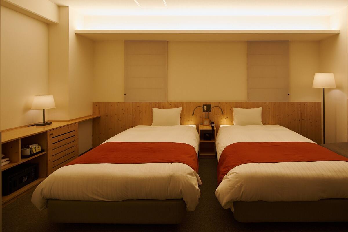 Une chambre d’hôtel avec deux lits, une table de chevet, une lampe et un canapé.