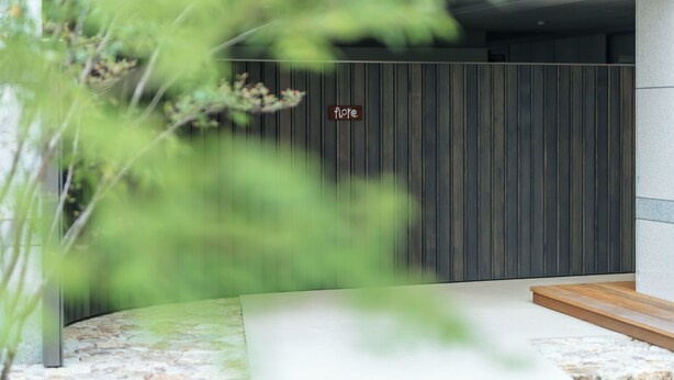 Une entrée moderne, avec un revêtement mural vertical en bois et une enseigne sur laquelle on peut lire « fique ».
