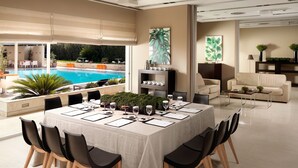 A modern dining area with a pool view, a sofa, and a coffee table. - Elefsina Hotel (Elefsina)