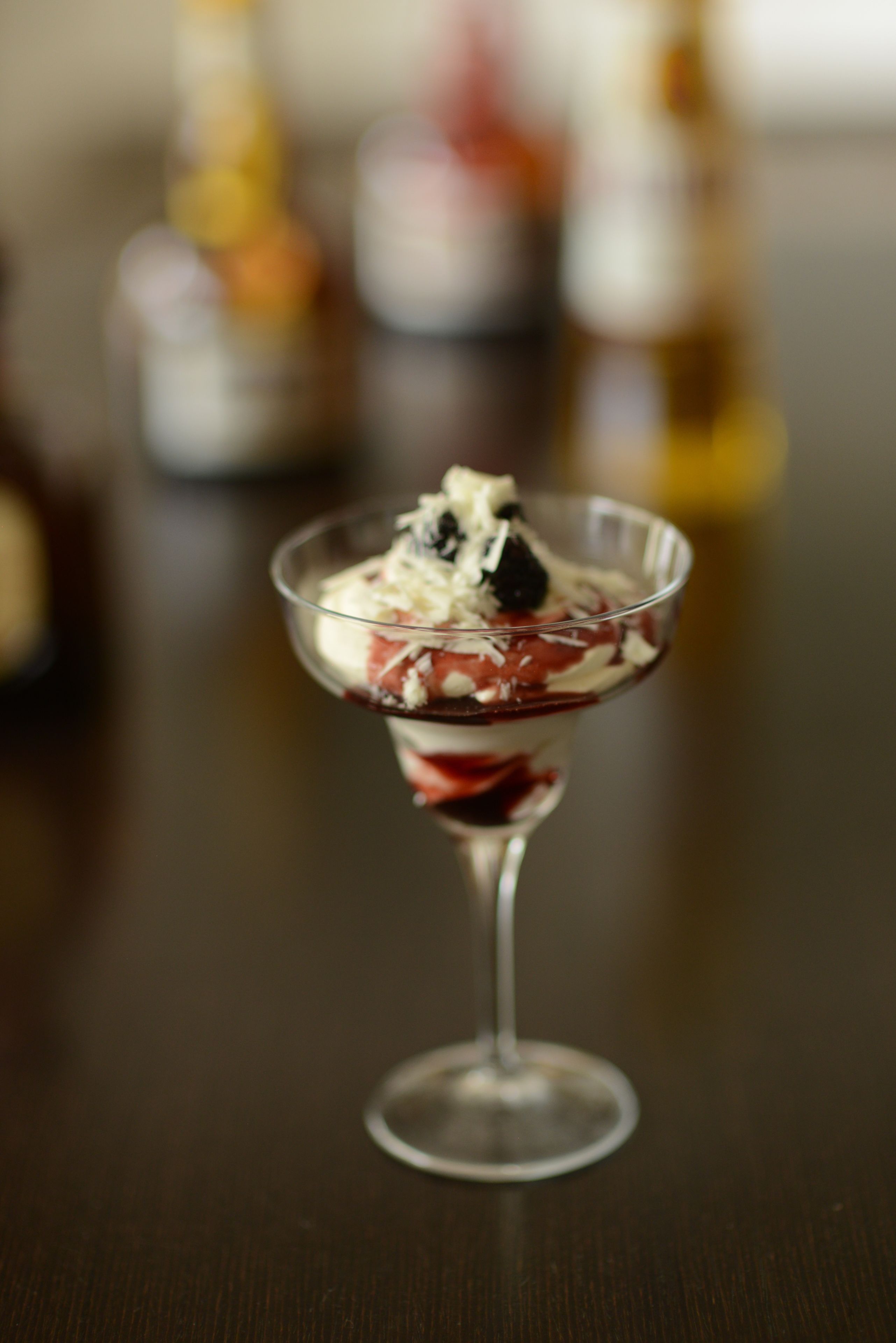 A dessert in a clear glass on a wooden table.