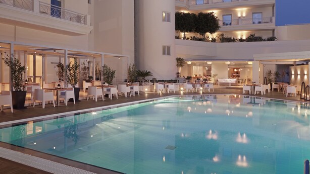 A hotel with a swimming pool, outdoor seating, and multiple balconies. - Elefsina Hotel (Elefsina)