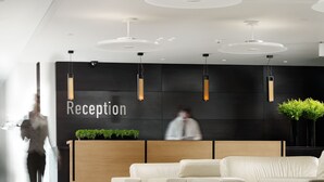 A modern reception area with a 'Reception' sign, a wooden reception desk, and a seating area with white sofas. - Elefsina Hotel (Elefsina)