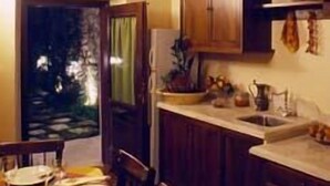 Une cuisine chaleureuse avec des meubles en bois, une table à manger pour quatre personnes et une vue sur l’extérieur par une fenêtre.