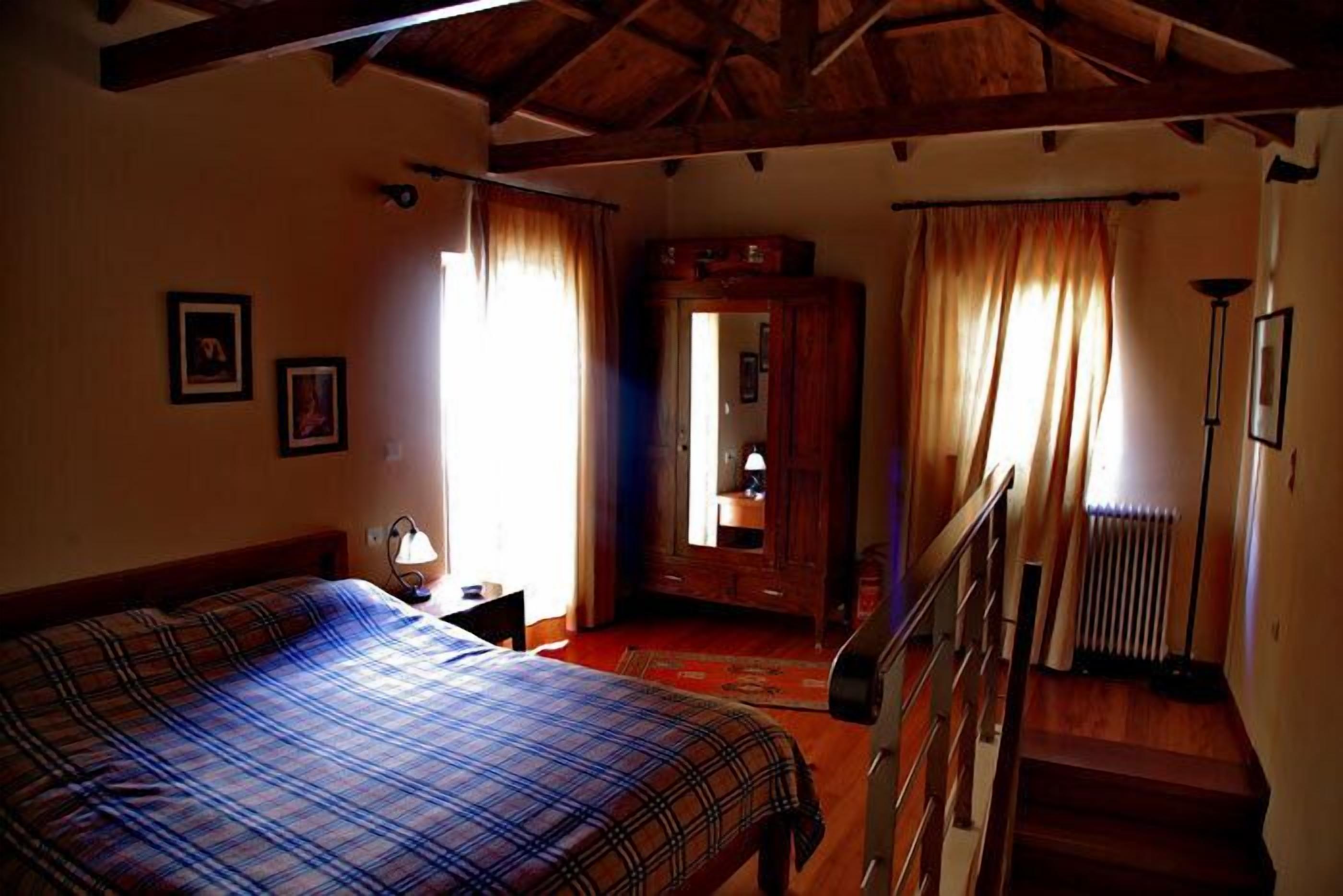 A bedroom with a bed, a nightstand, a dresser, a mirror, and a staircase.