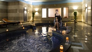 Wellnessbereich mit Whirlpool, Kerzen und einer Topfpflanze.