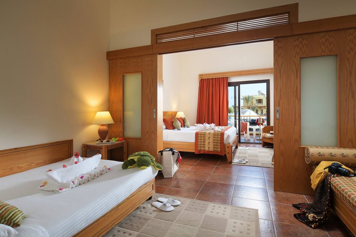 Habitación de hotel con dos camas, un área de descanso y vistas al exterior.