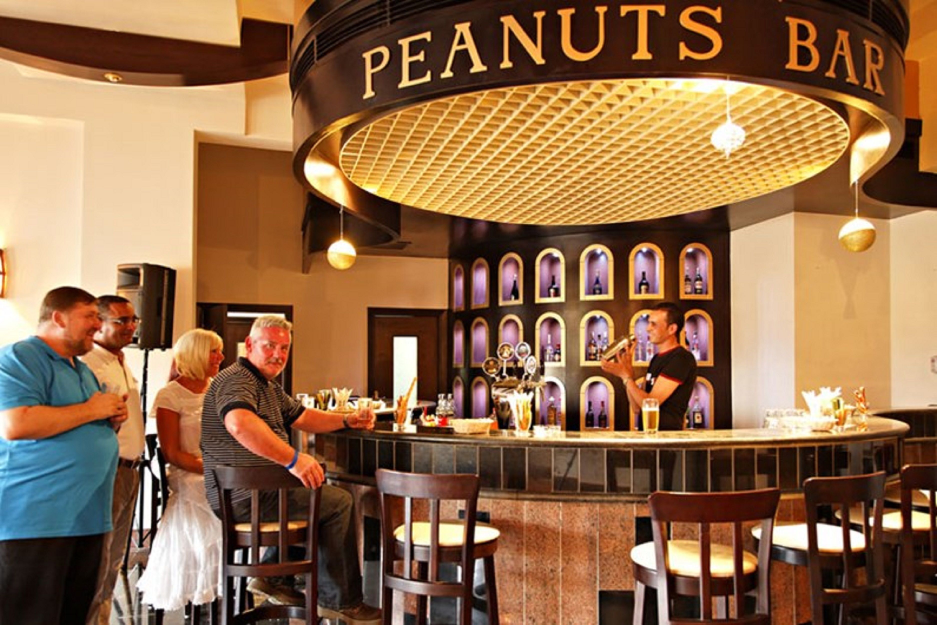 A bar area with a sign reading "PEANUTS BAR," featuring a circular ceiling design and multiple seating arrangements.