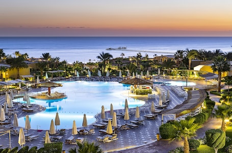 Una piscina al aire libre, sombrillas, sillones reclinables de piscina