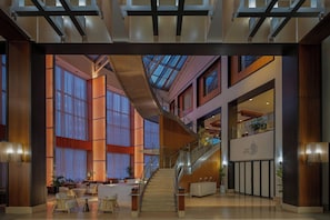 A spacious lobby with a central staircase, large windows, and a reception desk.