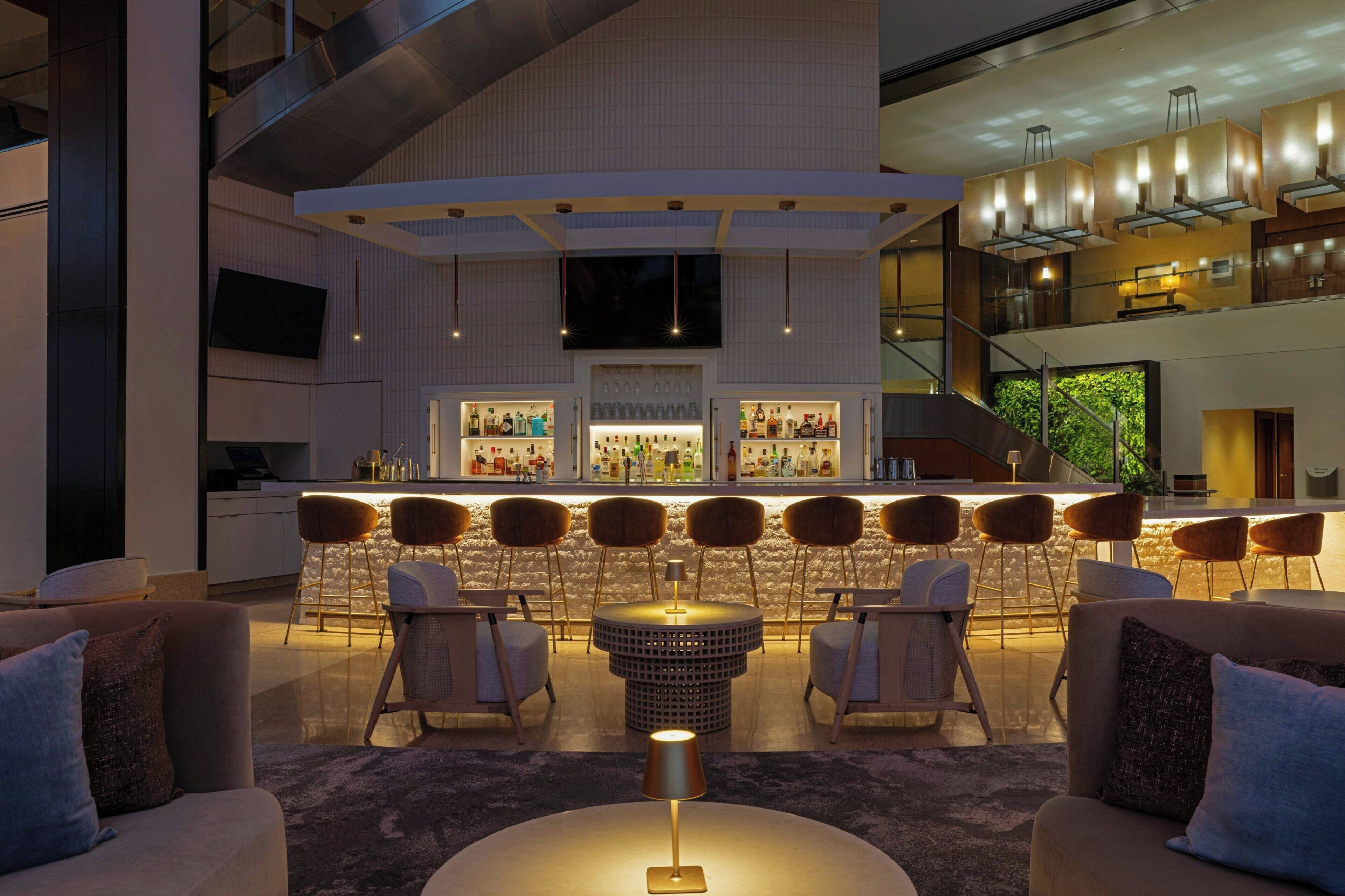 A modern bar area with seating, a round table, and a staircase.
