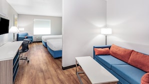A modern hotel room with a desk, two beds, a sofa, and a TV. - Days Inn & Suites by Wyndham San Antonio near Frost Bank Center (San Antonio)