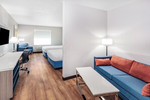 A modern hotel room with a desk, two beds, a sofa, and a TV. - Days Inn & Suites by Wyndham San Antonio near Frost Bank Center (San Antonio)