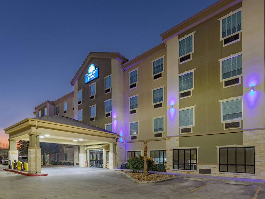 Ein Hotel mit überdachter Eingangsparte, mehreren Etagen und einem Schild, das es als Days Inn & Suites kennzeichnet.