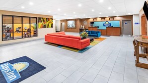 A hotel lobby with a reception desk, a red sofa, and a large painting on the wall. - Days Inn & Suites by Wyndham San Antonio near Frost Bank Center (San Antonio)