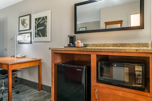 Ein Hotelzimmer mit Schreibtisch, Kaffeemaschine, Kühlschrank und Mikrowelle.