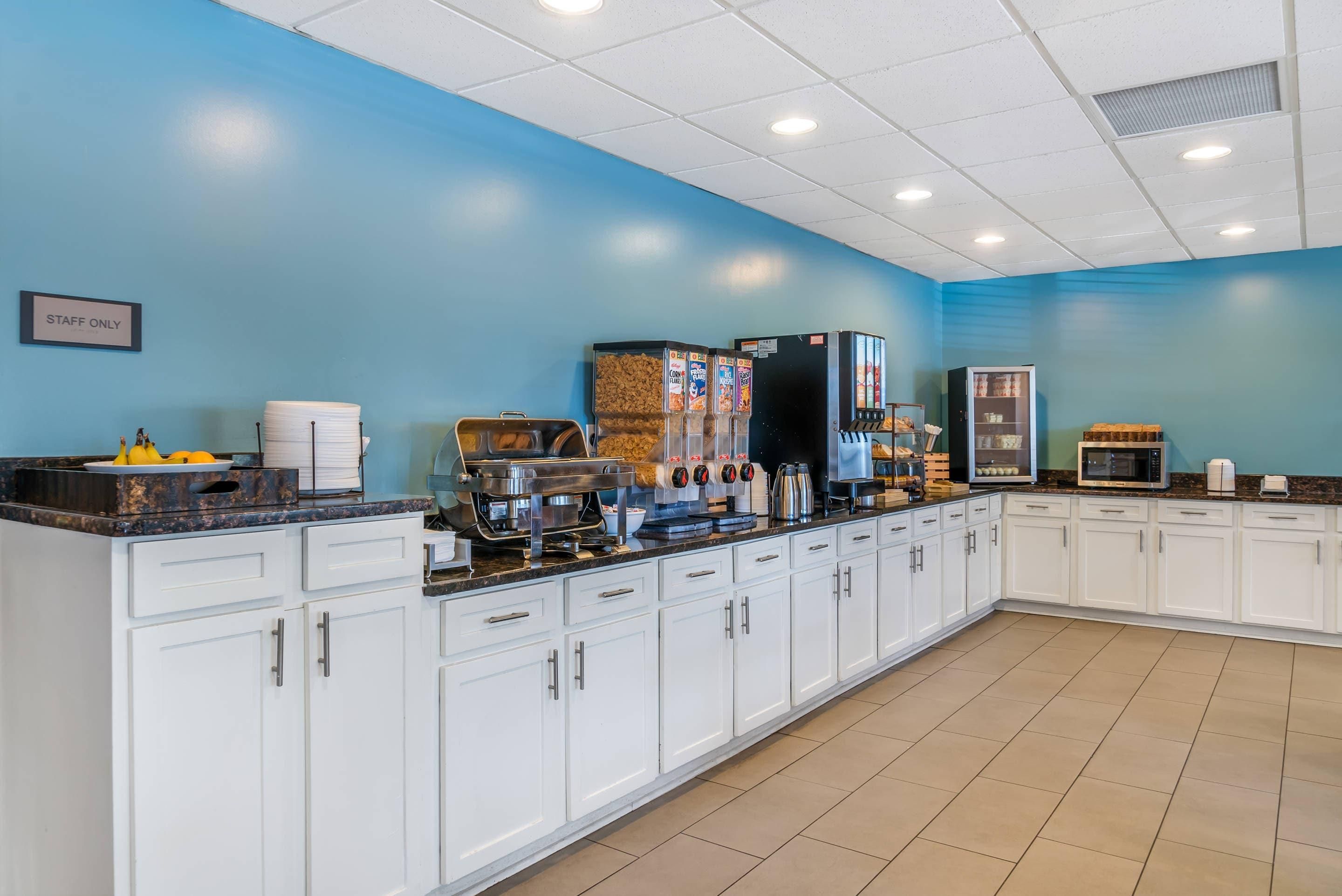 A kitchen area with a coffee station, a refrigerator, and a microwave.
