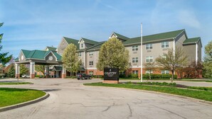 A multi-story hotel with a covered entrance, a sign reading "Country Inn & Suites," and a parking lot with cars.