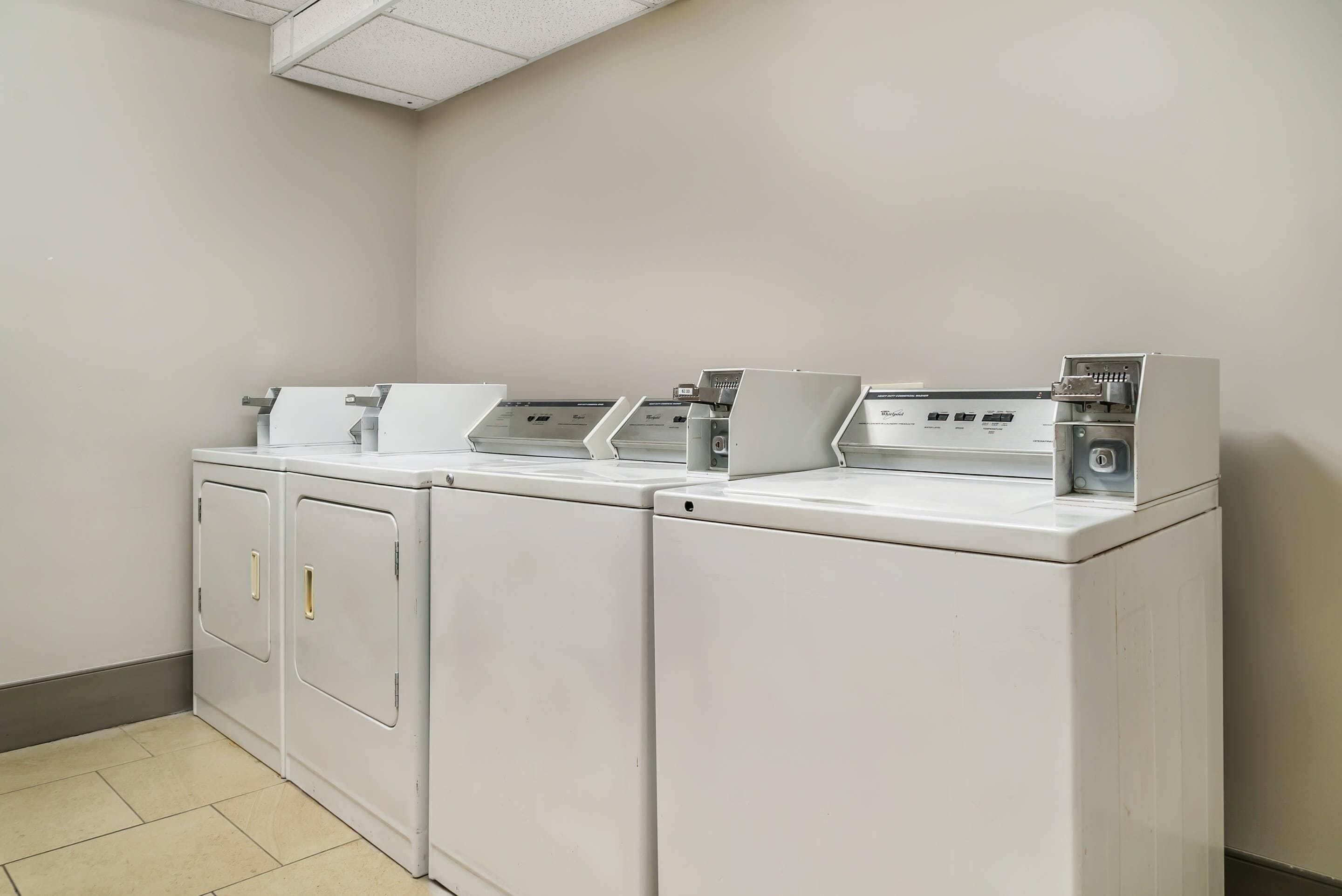 A laundry facility with two front-loading washing machines and a dryer.