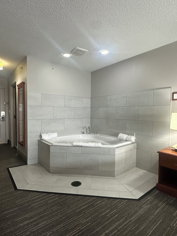 A modern bathroom with a freestanding bathtub, a mirror, and a wooden side table.