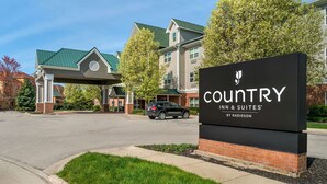 A Country Inn & Suites by Radisson sign in front of a building with a green roof and brick facade.