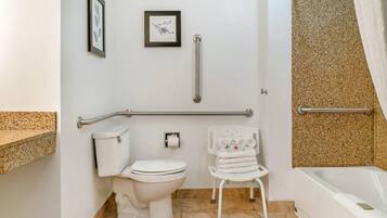 A bathroom with a toilet, a handrail, a towel rack, and a shower area.