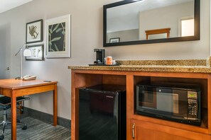 Habitación de hotel con escritorio, cafetera, refrigerador y microondas.