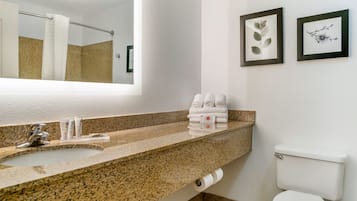 Ein Badezimmer mit Marmorwaschtisch, Spiegel, Toilette und gerahmten Kunstwerken an der Wand.