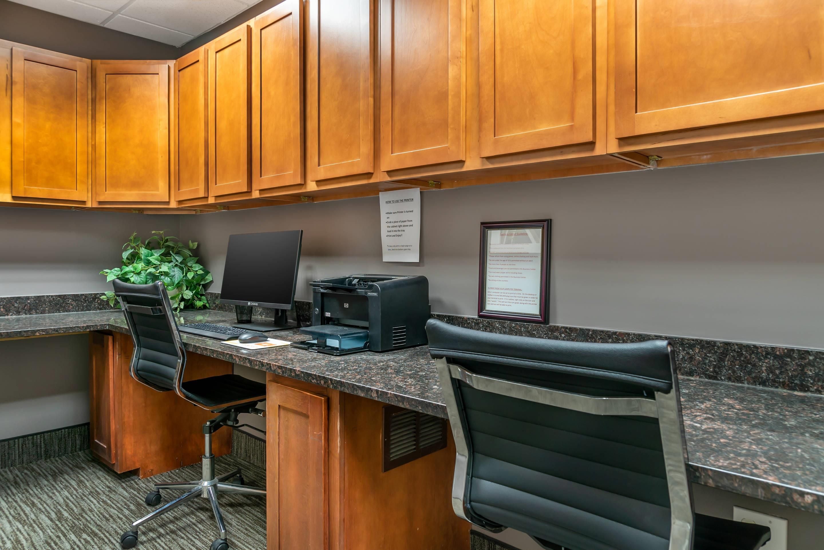 A professional office space with wooden cabinets, a desktop computer, two office chairs, and a printer.