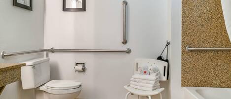 Une salle de bain équipée de toilettes, d’un lavabo, d’un porte-serviettes et d’une barre d’appui.