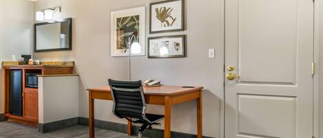 Une chambre d’hôtel équipée d’un bureau, d’une chaise, d’une kitchenette et d’une porte.