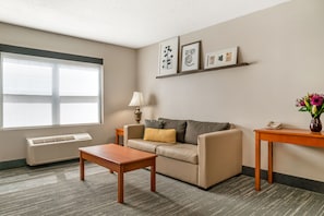 A living room with a sofa, a coffee table, a lamp, a side table, and framed artwork on the wall.