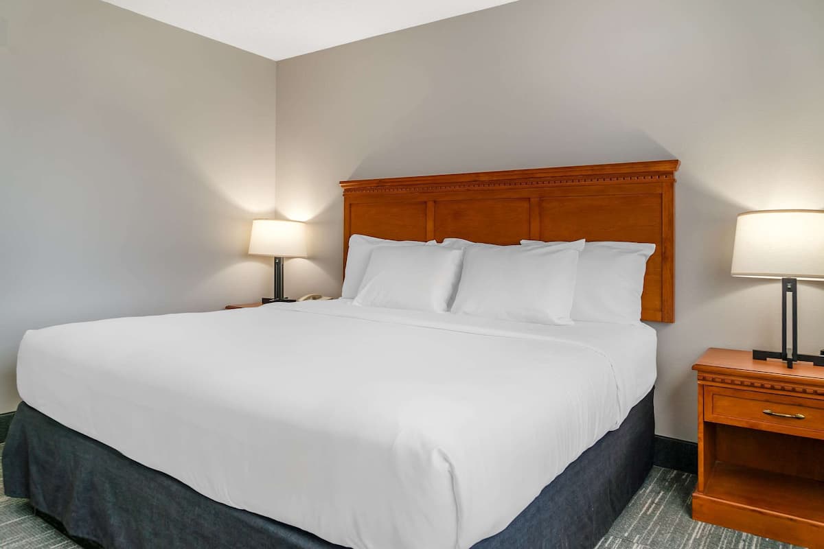A hotel room with a large bed, two bedside tables with lamps, and a wooden headboard.